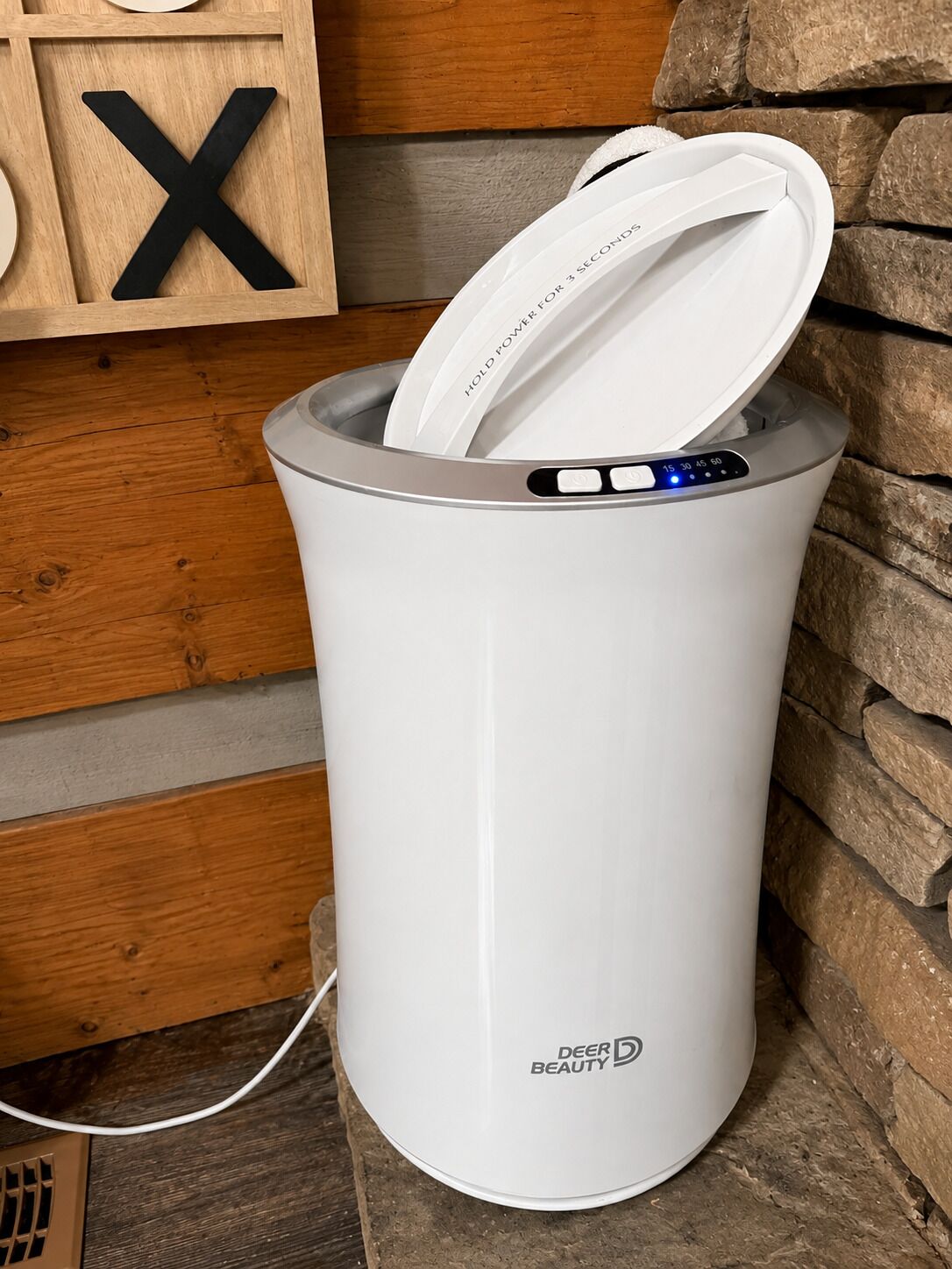 A white electric kettle with a control panel and a power cord plugged in.