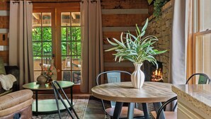 Une pièce chaleureuse avec une cheminée, une table ronde en bois et une plante en pot.