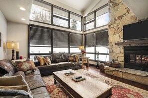 A cozy living room with a stone fireplace, leather sofa, and large windows. - Perfect location, walk to Main St! RENOVATIONS complete for 2025/2026! (Park City)