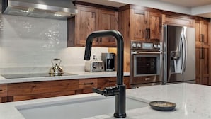 A modern kitchen with wooden cabinets, stainless steel appliances, and a marble countertop.