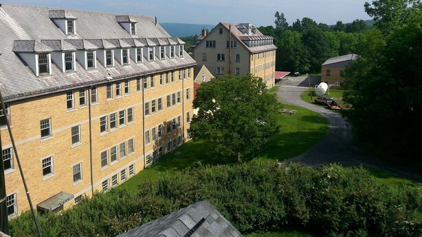 Un grand immeuble à plusieurs étages, doté d’une section centrale imposante et d’une section plus petite située à droite.