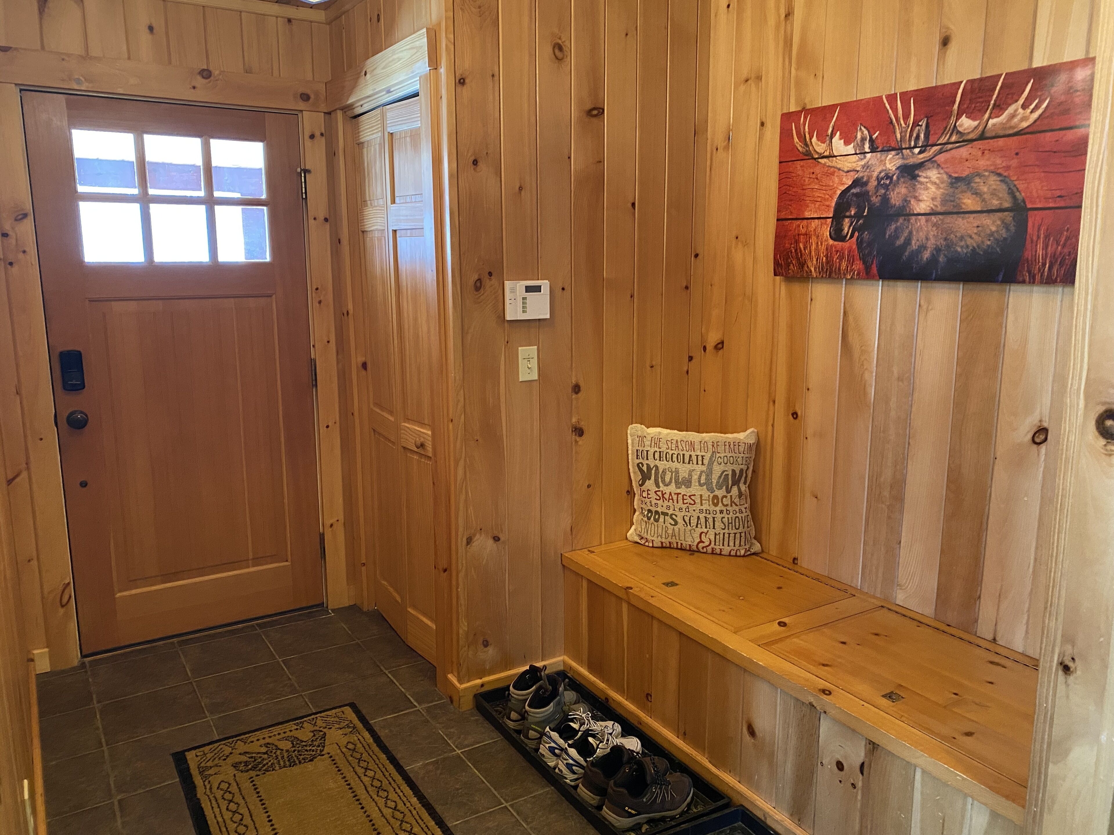 Un intérieur en bois avec un banc, une porte et un tableau représentant un élan, accroché au mur.