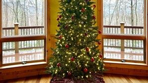 A Christmas tree with lights and ornaments in a room with wooden floors and large windows. - True North at Sunday River-Powder Ridge-4miles to Mtn. New Air Conditioning !! (Newry)