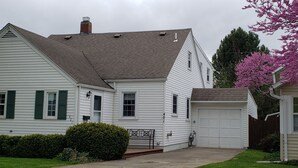 Une maison de plain-pied avec un garage, un porche à l’avant et une pelouse bien entretenue.