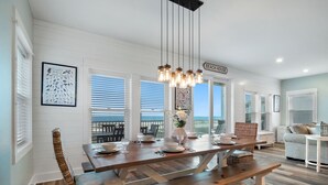 Ein Essbereich mit einem Holztisch, gedeckt für vier Personen, weißen Wänden und einem Schild mit der Aufschrift 'BEACH HOUSE'.