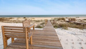 Eine hölzerne Promenade führt zu Strandbänken mit freiem Blick auf das Meer.