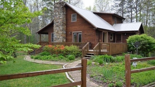 Un rustico cottage in legno con un camino in pietra, un patio in legno e un giardino curato.