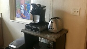 Eine kleine Küchenzeile mit Kaffeemaschine, Toaster und Mülleimer.