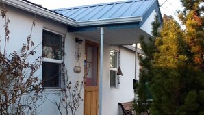 Ein Haus mit blauem Dach, einer Holztür und einer kleinen Veranda mit einer Bank.