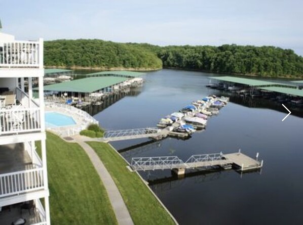 A marina with multiple docks and boats, a swimming pool, and a building with balconies.