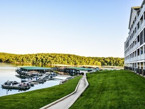 A marina with boats docked, a grassy area, and a building with a modern design.