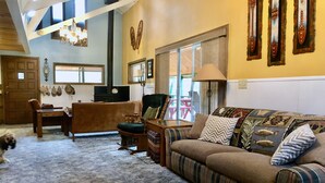 A cozy living room with a sofa, chairs, a fireplace, and a large window.