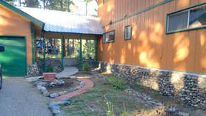 A building with a green garage door, a covered porch, and a stone wall.