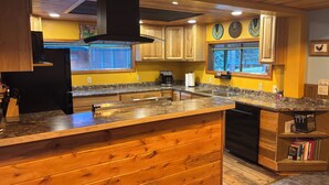 A kitchen with wooden cabinets, granite countertops, a built-in island, and a window with a view.