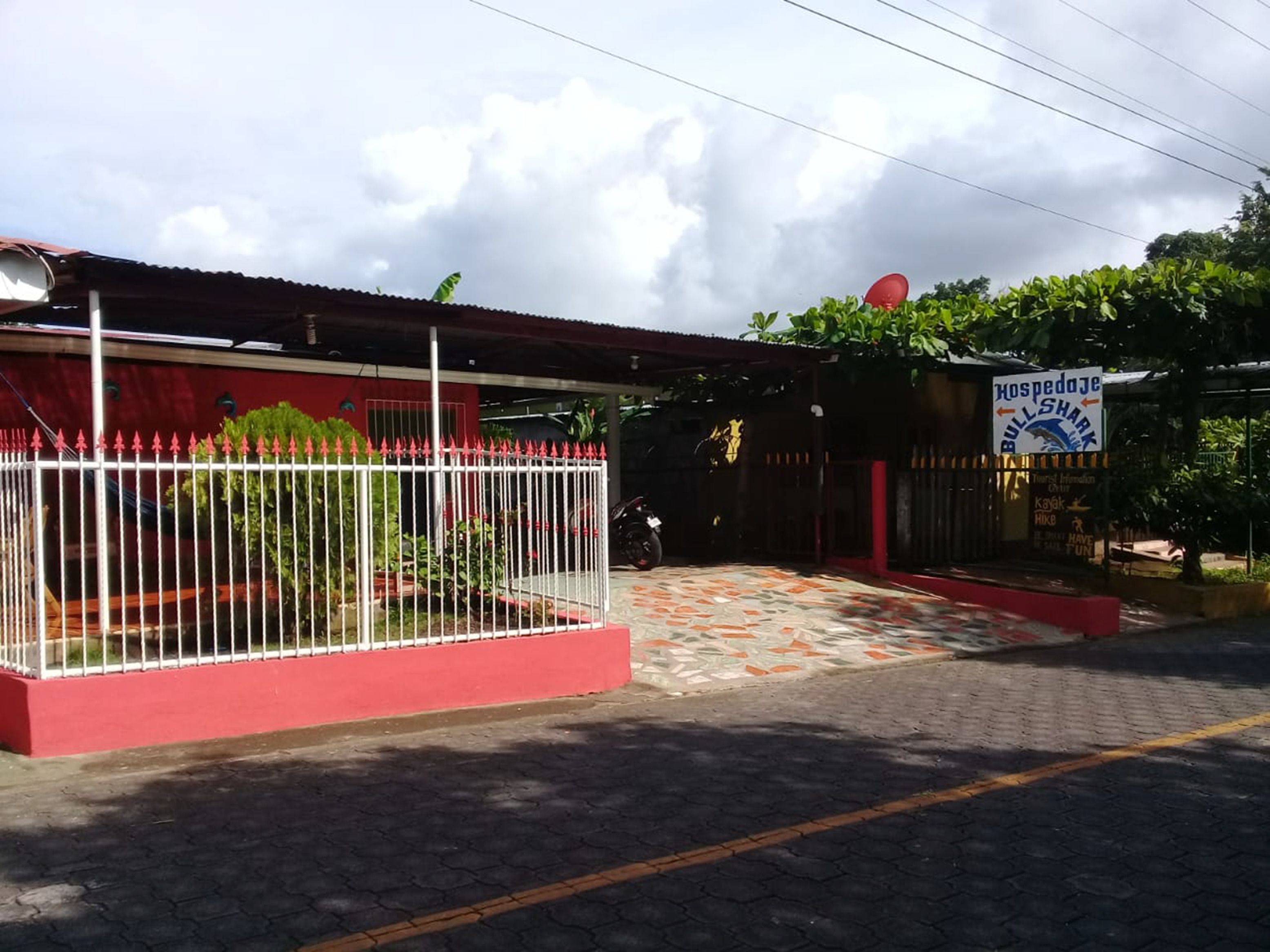 A building with a red facade, a white fence, and a sign advertising bull shark fishing.