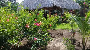 Una cabaña con techo de paja rodeada de exuberante follaje y plantas florecientes.