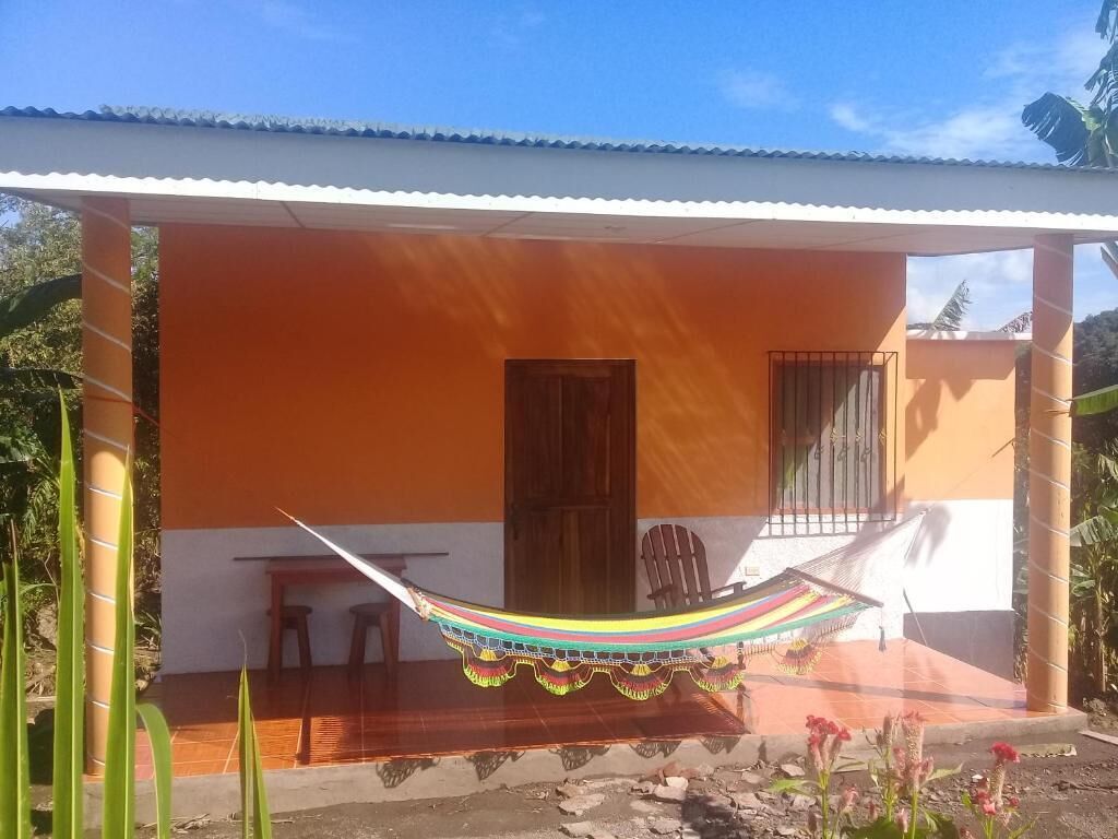 Una casa con porche, una hamaca y una puerta de madera.