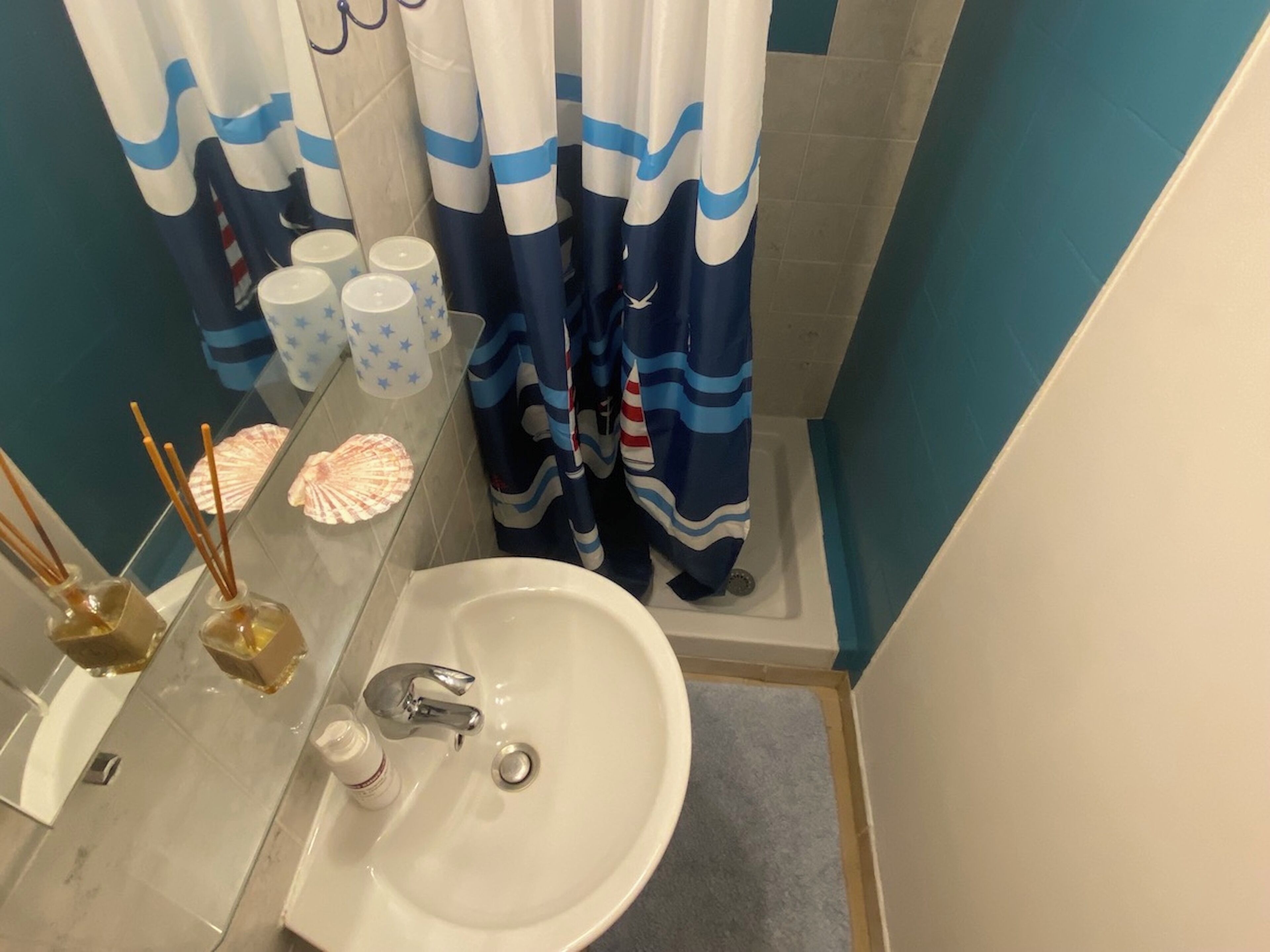 A bathroom with a sink, mirror, and shower curtain.