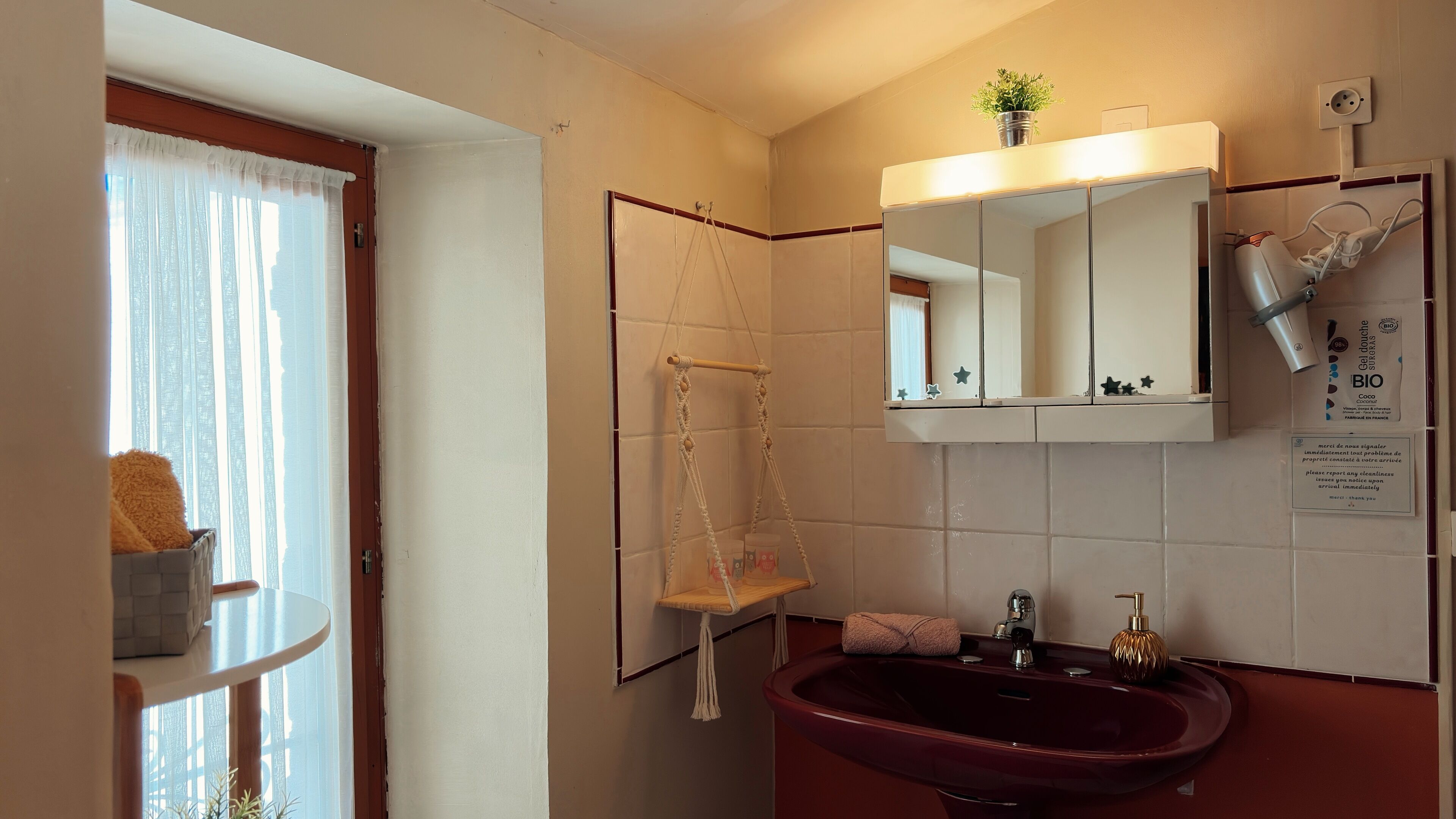 Une salle de bain avec un lavabo rouge, un miroir, un porte-serviettes et une petite étagère contenant des articles de toilette.