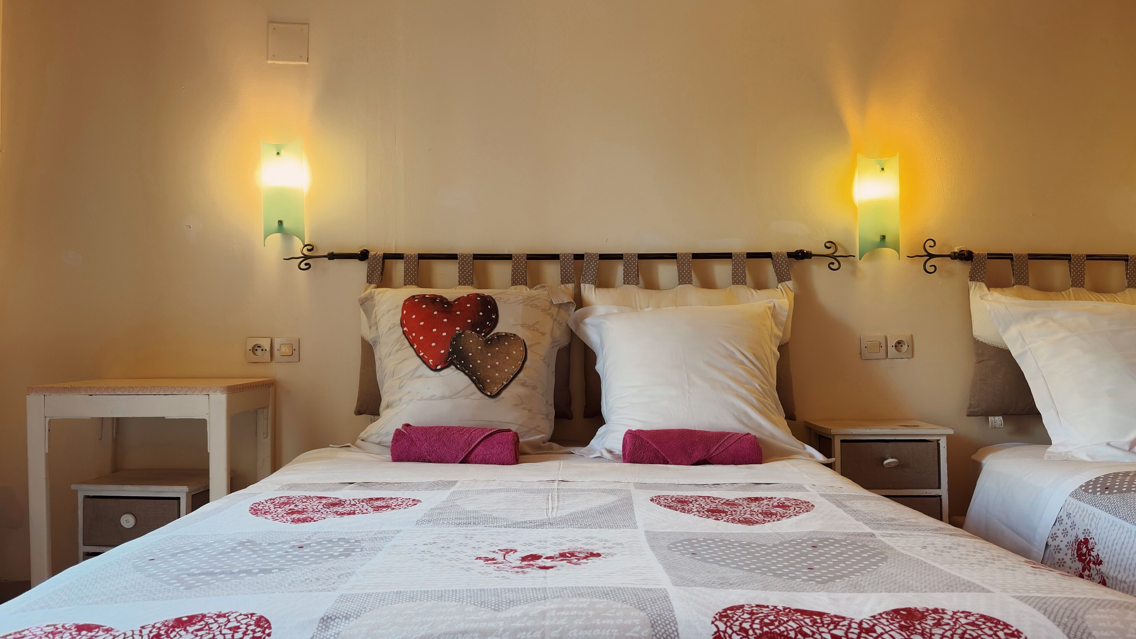 A hotel room with a bed, two bedside tables, and wall-mounted lights.