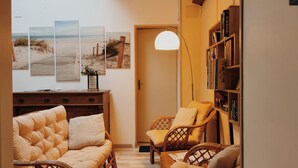 Un salon confortable avec un grand canapé moelleux, un fauteuil en osier et une bibliothèque.