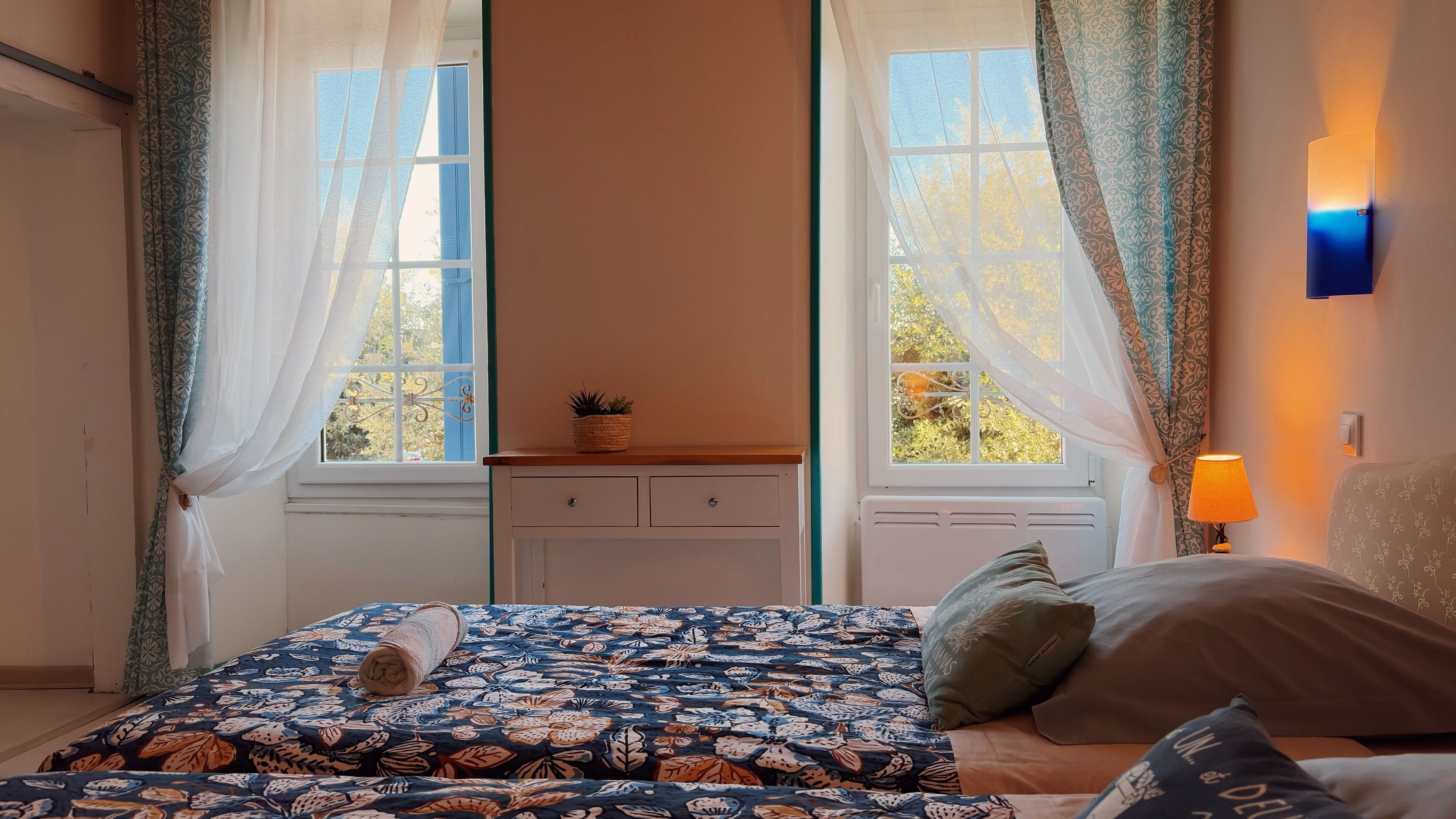 A bedroom with a bed, a nightstand, a lamp, and a window with curtains.