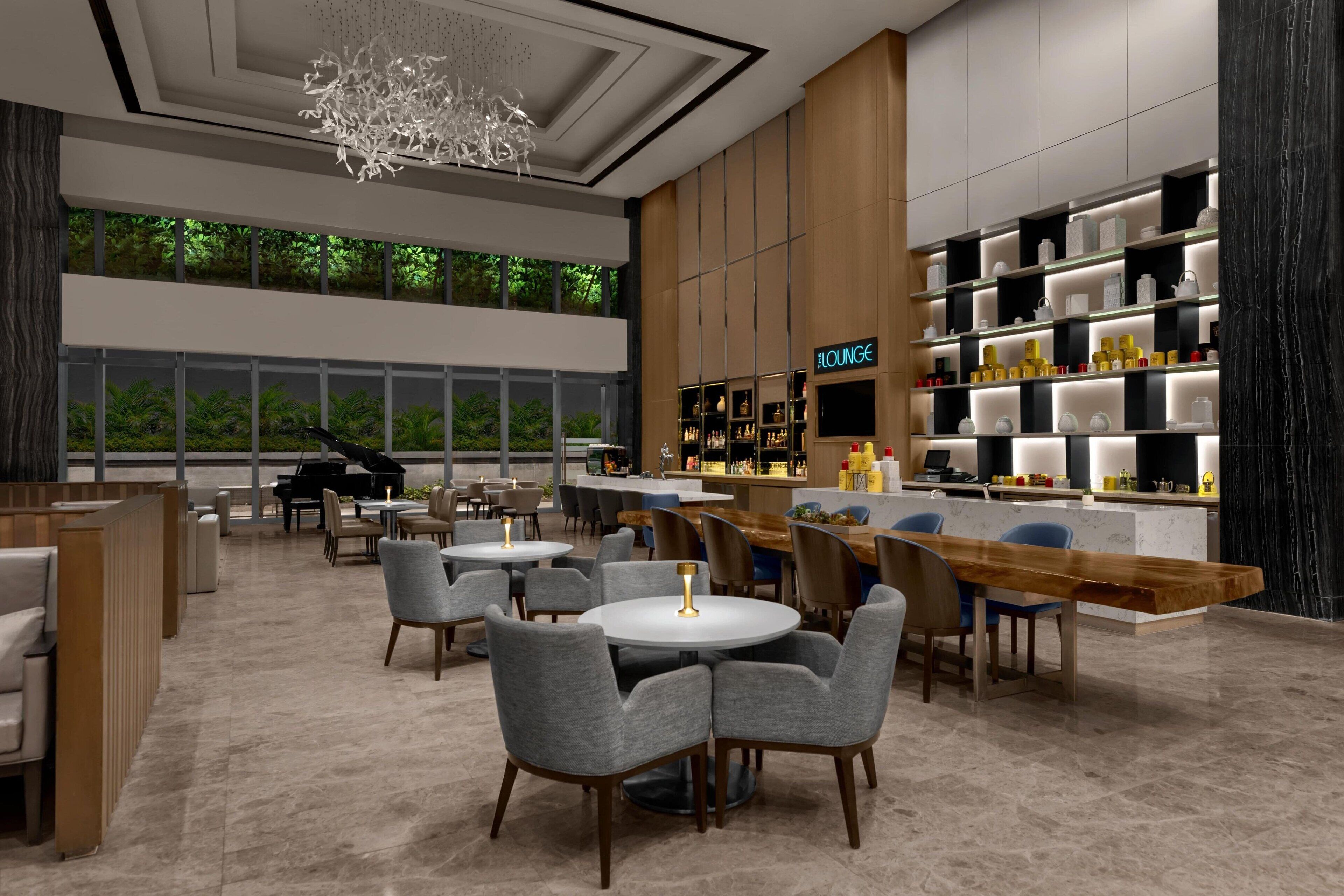 A modern lounge area with seating, a piano, and a bar with shelves of bottles.
