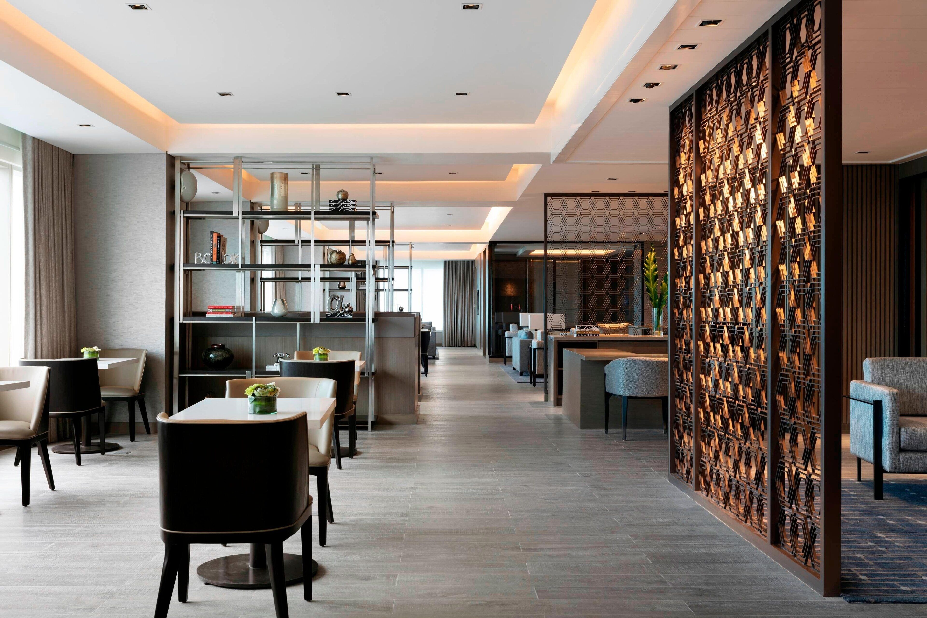 Eine moderne Hotelhalle mit einer langen Rezeption, einer Sitzecke und einer Wand mit geometrischen Mustern.