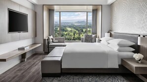 A modern hotel room with a large bed, a TV, a seating area with a view, and a decorative wall. - Clark Marriott Hotel (Mabalacat City)