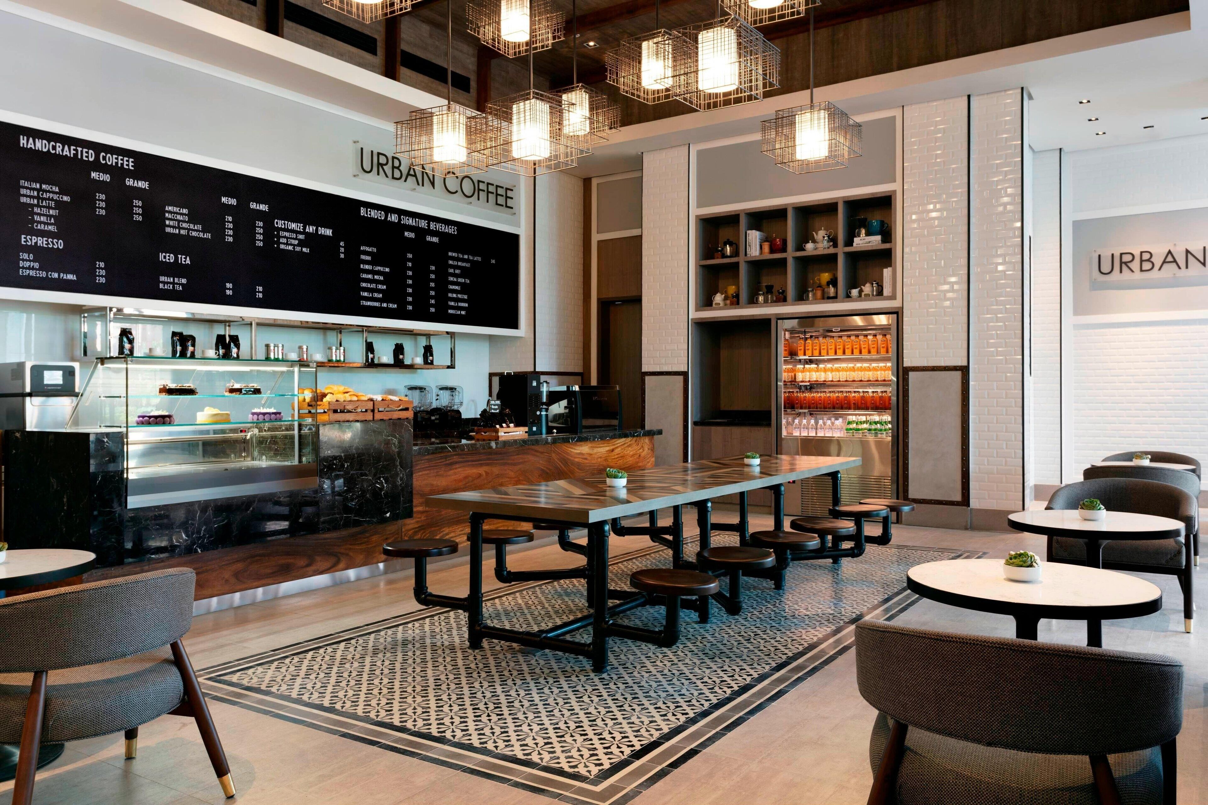 A modern coffee shop interior with a menu board, seating area, and beverage display.