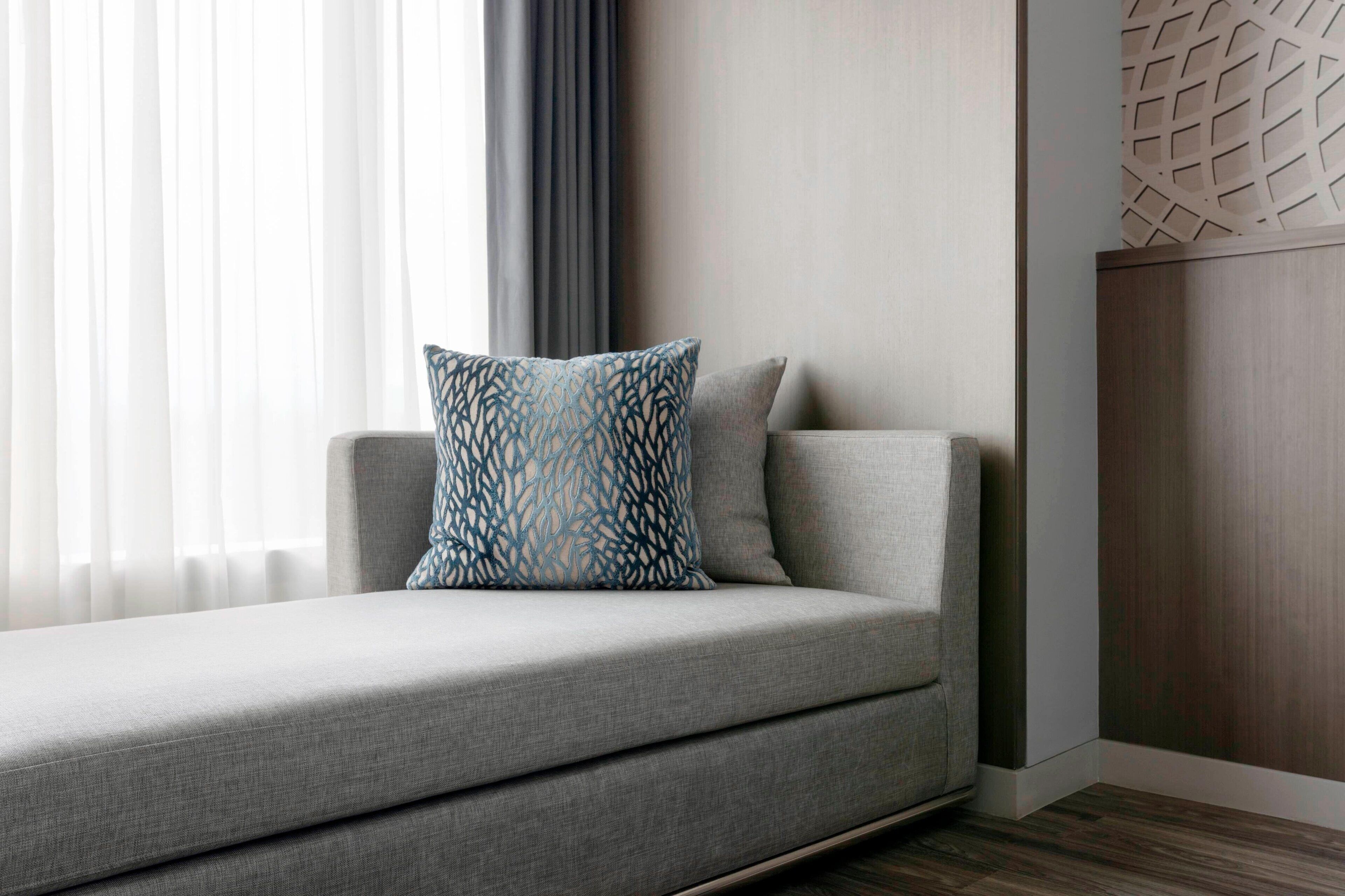 Una sala de estar moderna con un sofá gris, un cojín decorativo estampado y una pared de acento de madera.