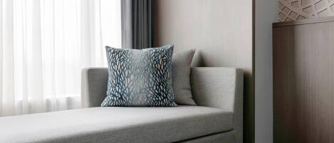Una sala de estar moderna con un sofá gris, un cojín decorativo estampado y una pared de acento de madera.