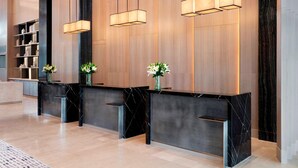 A reception area with a marble counter, black marble base, and three pendant lights. - Clark Marriott Hotel (Mabalacat City)