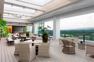 A spacious outdoor patio with wicker furniture, a bar area, and a view of the landscape.