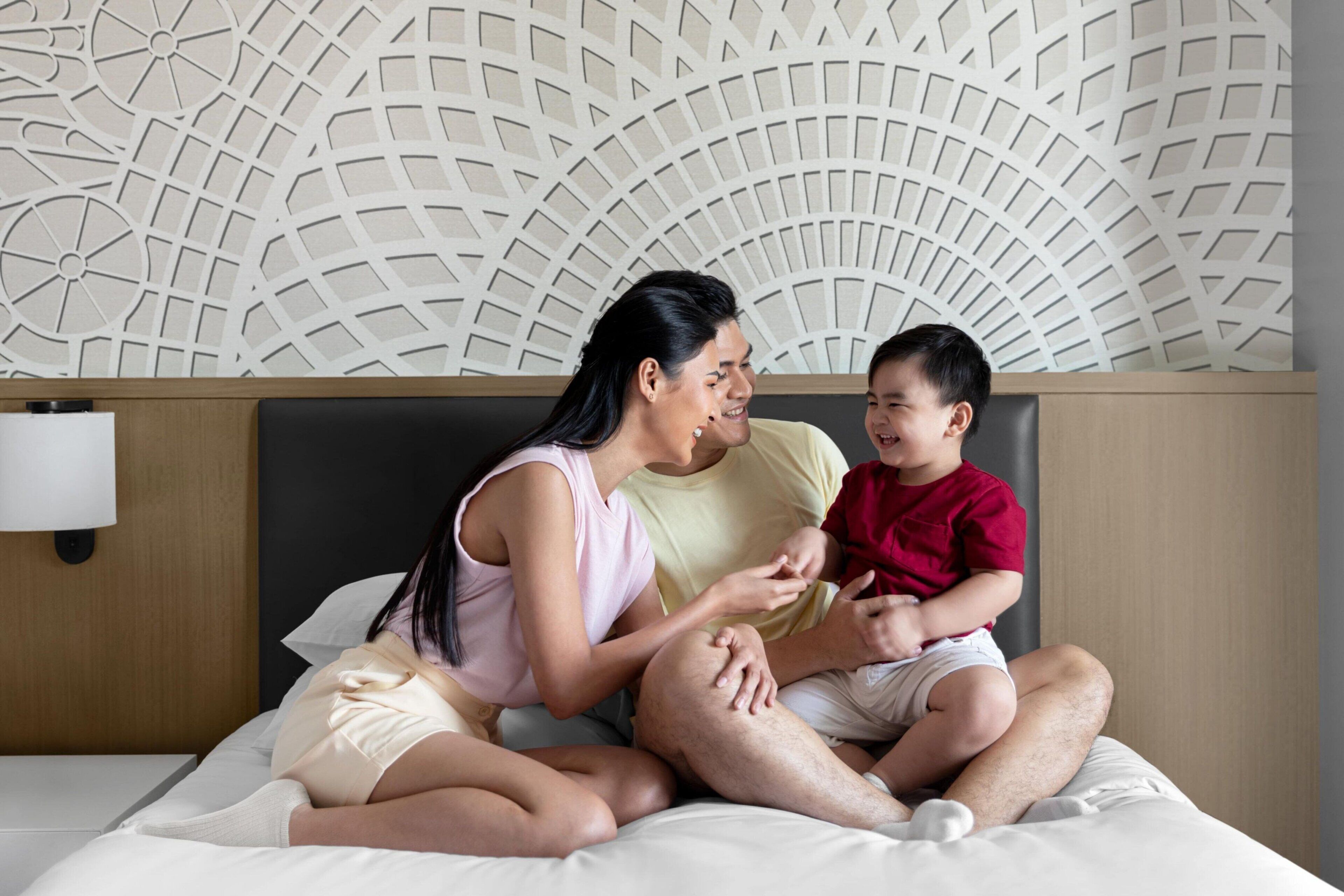 Una cama con un cabecero decorativo, una lámpara de noche y una pared con un diseño geométrico.