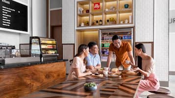 A modern cafe with a wooden counter, a menu board, and a shelf with various items.