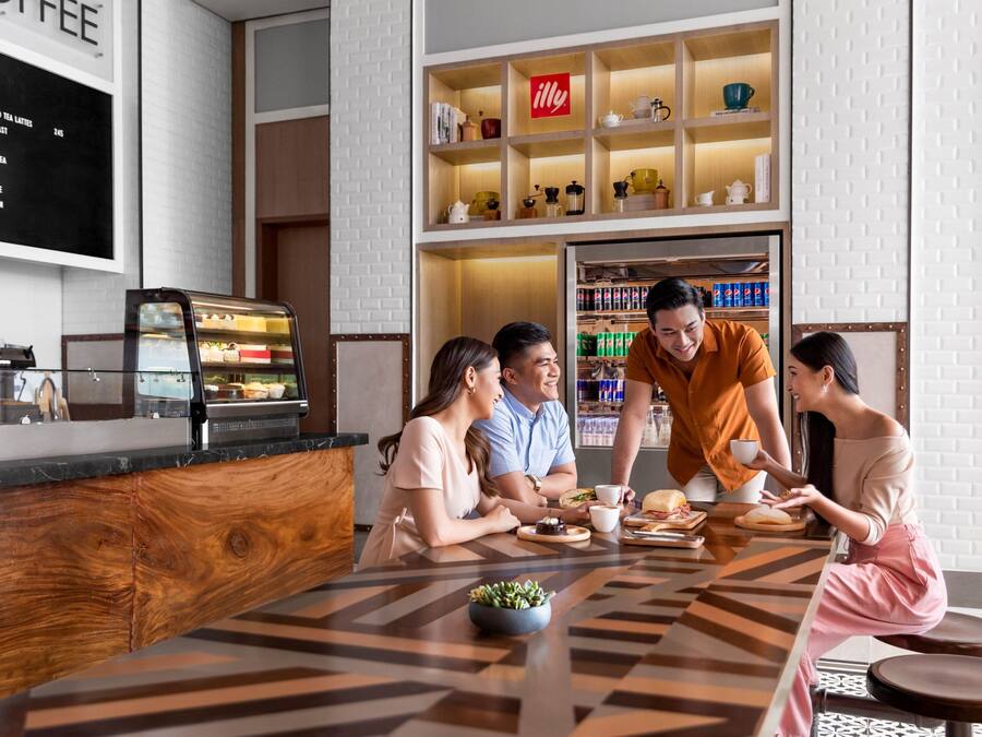 A modern cafe with a wooden counter, a menu board, and a shelf with various items.