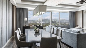 A modern hotel room with a dining area, a sofa, and a large window offering a city view. - Clark Marriott Hotel (Mabalacat City)