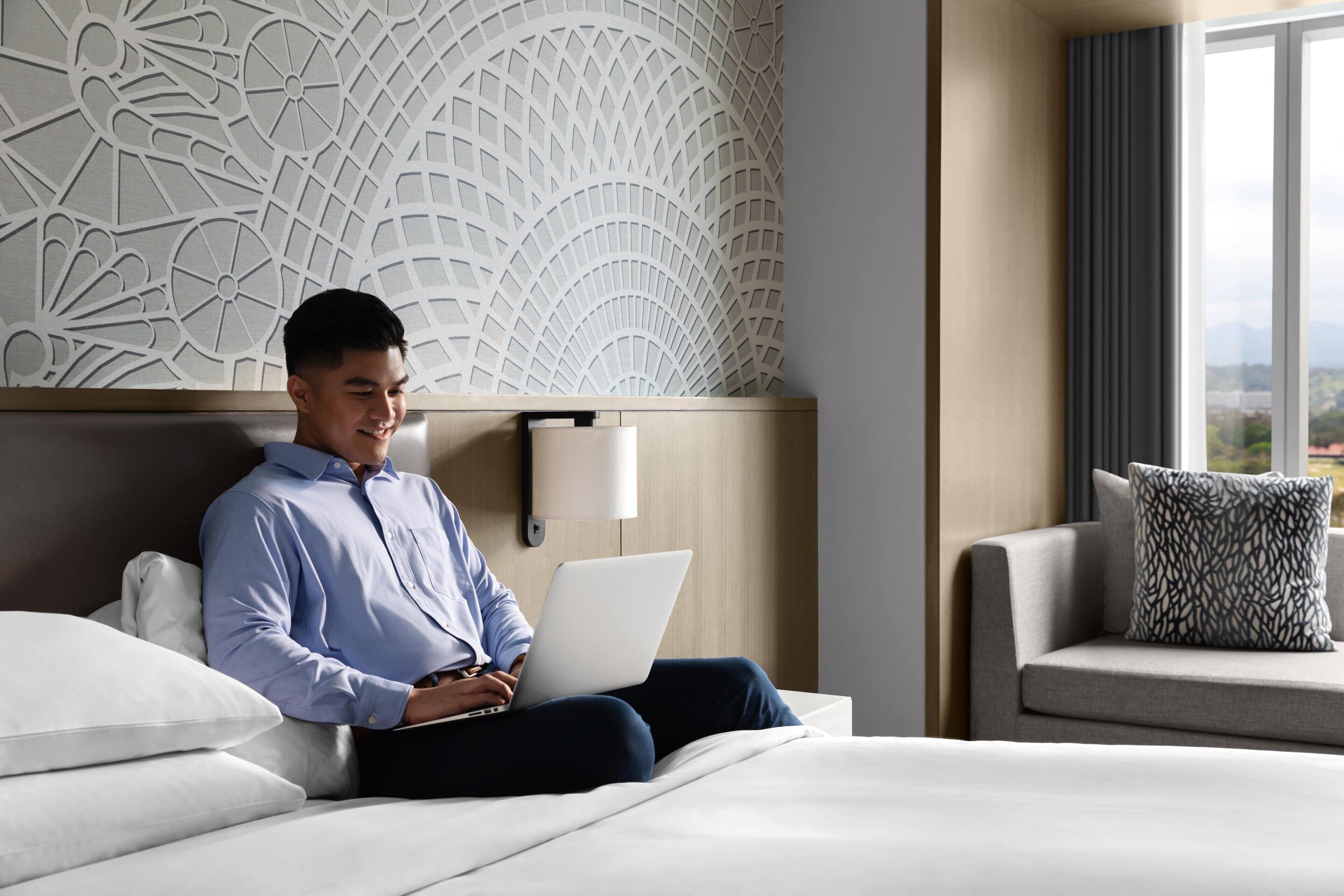 A hotel room with a bed, a sofa, a lamp, and a decorative wall panel.