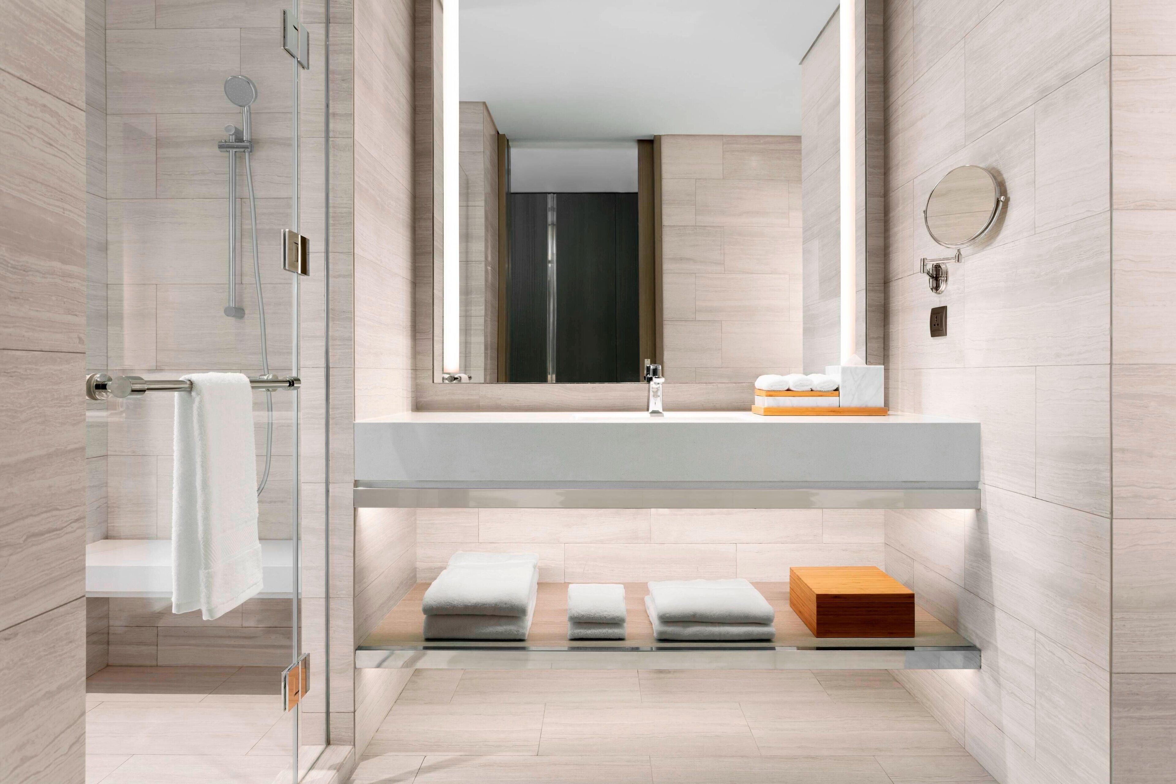 Un baño moderno con ducha de vidrio, un espejo grande y un diseño minimalista.