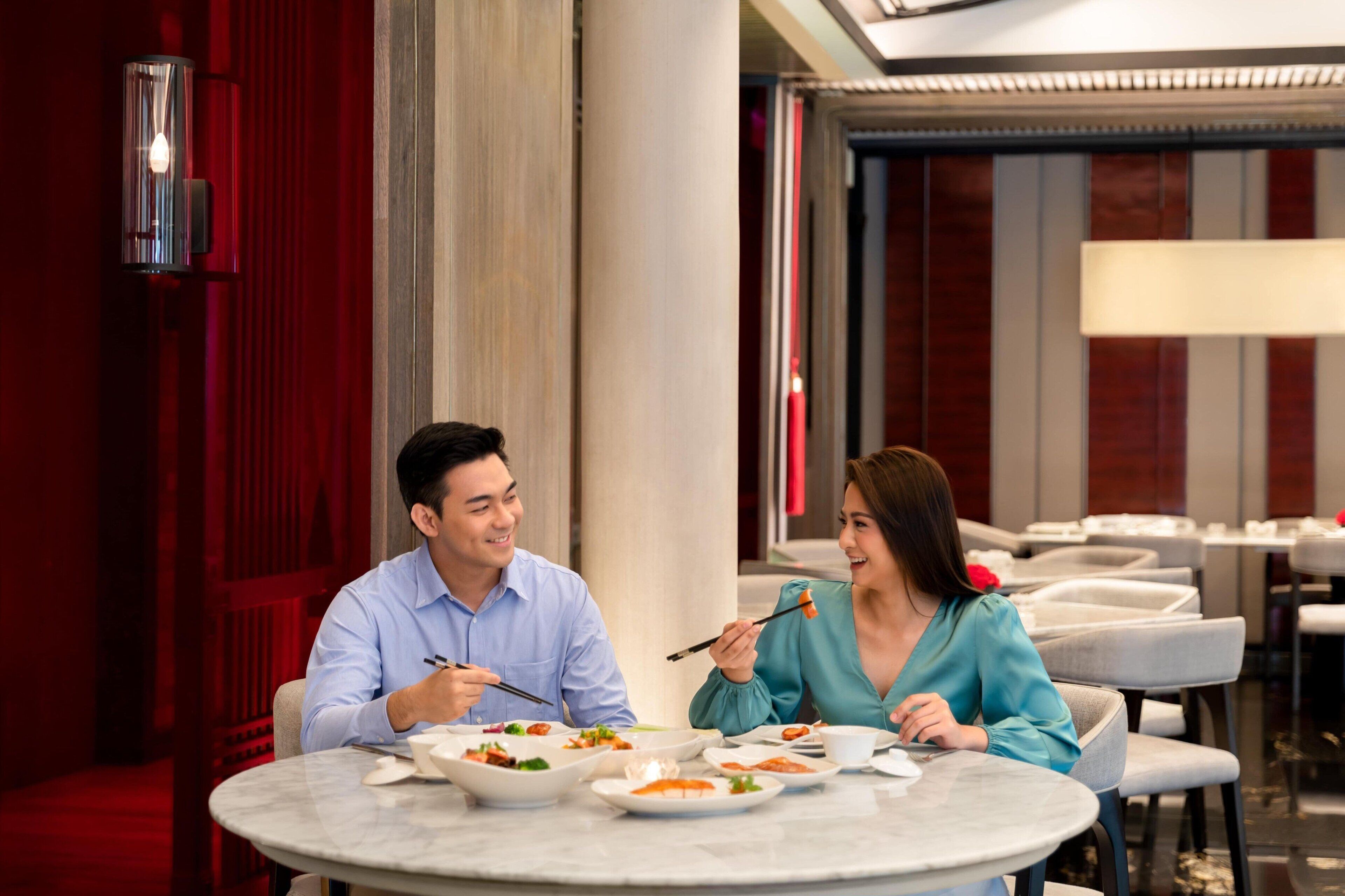 A dining area with round tables, chairs, and a red curtain backdrop.