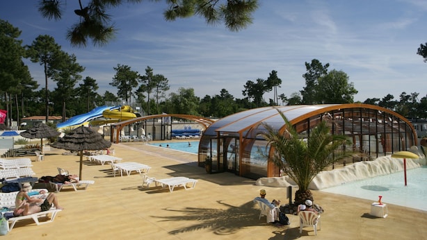 Area piscina con sdraio, scivolo acquatico e zona relax coperta.