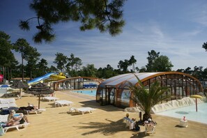 Ein Poolbereich mit Liegestühlen, einer Wasserrutsche und einem überdachten Sitzbereich.