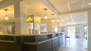 Un'area bar moderna con un bancone, luci a sospensione e un cartello Corona.