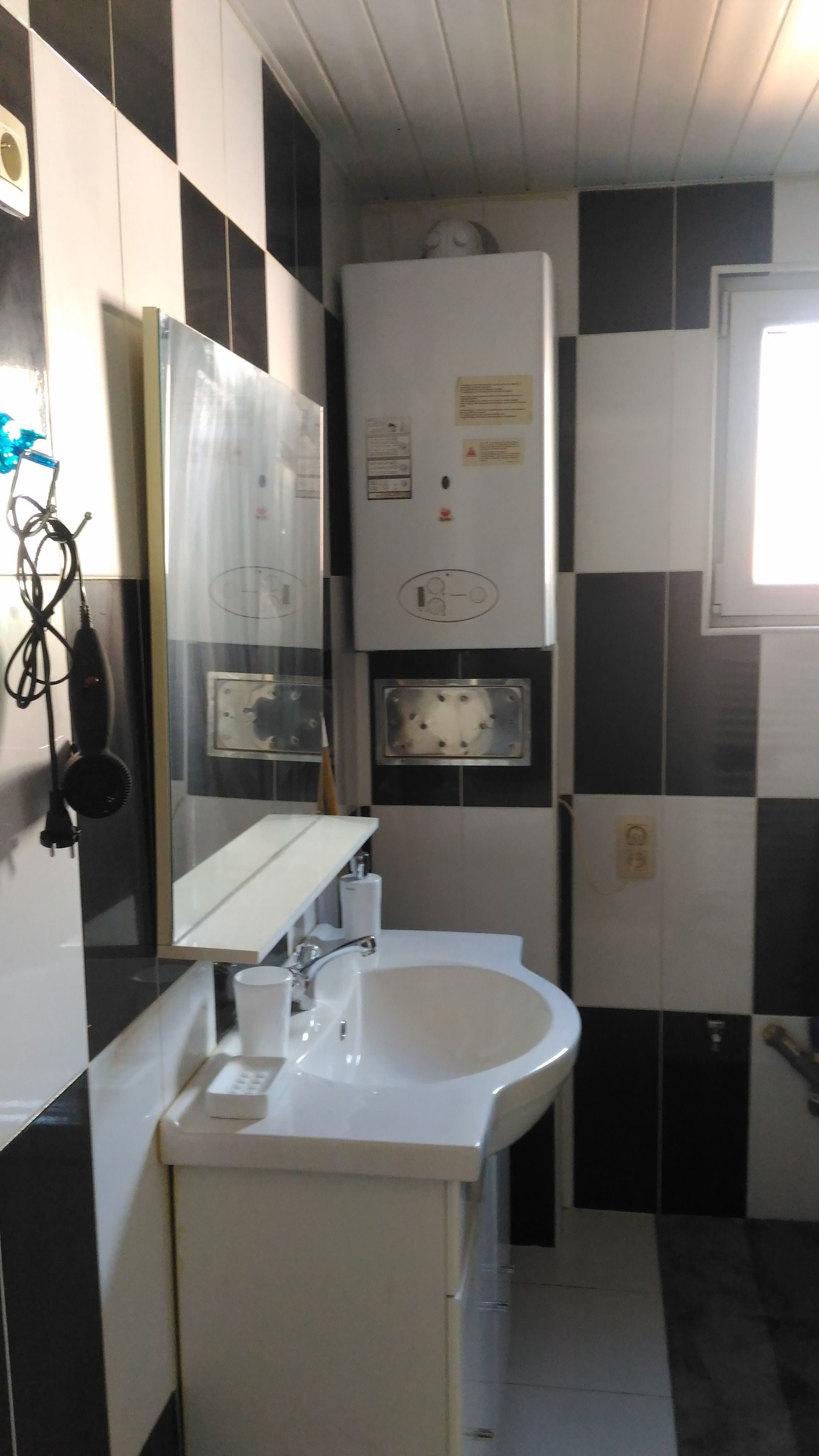 A bathroom with a white sink, a mirror, and a towel rack. There is a window with a view of the outside.