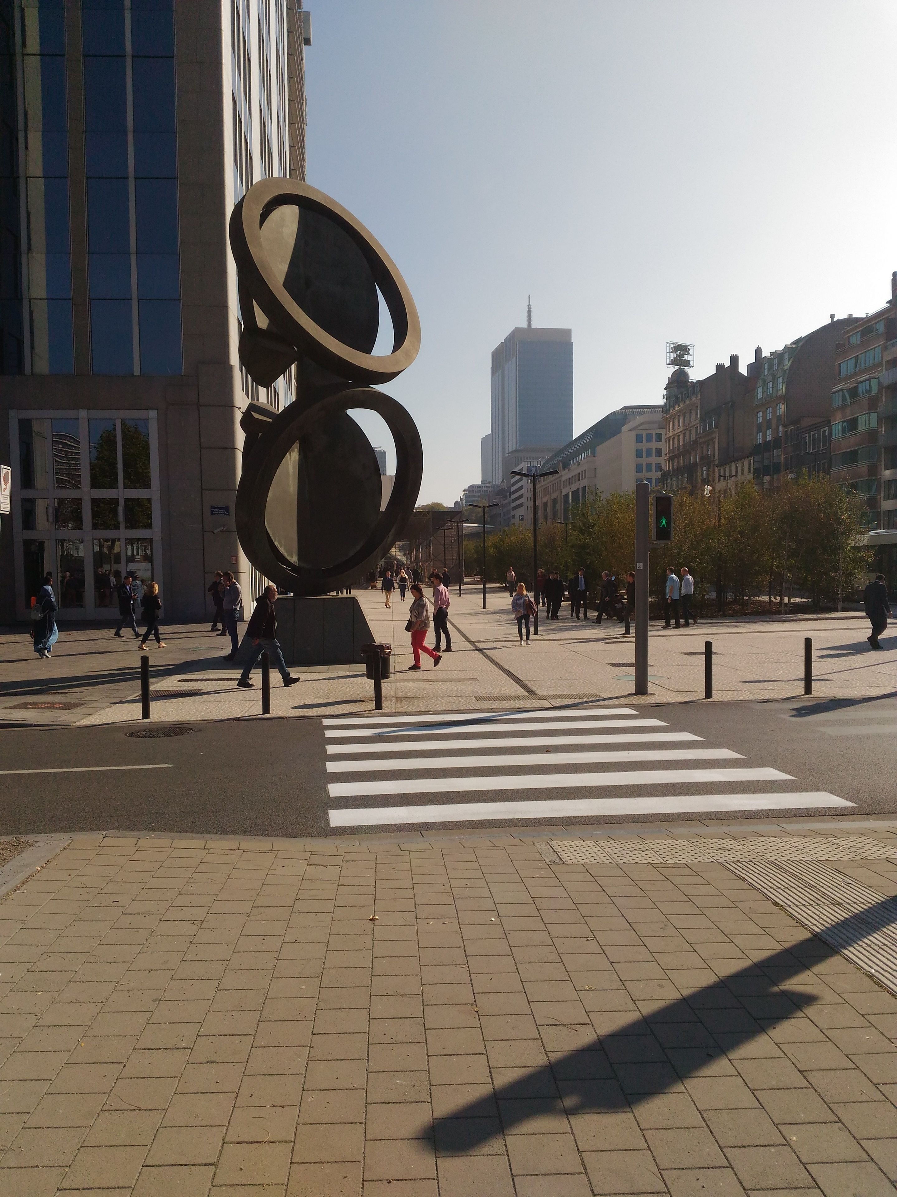 Un passage piéton agrémenté d’une sculpture moderne en premier plan.