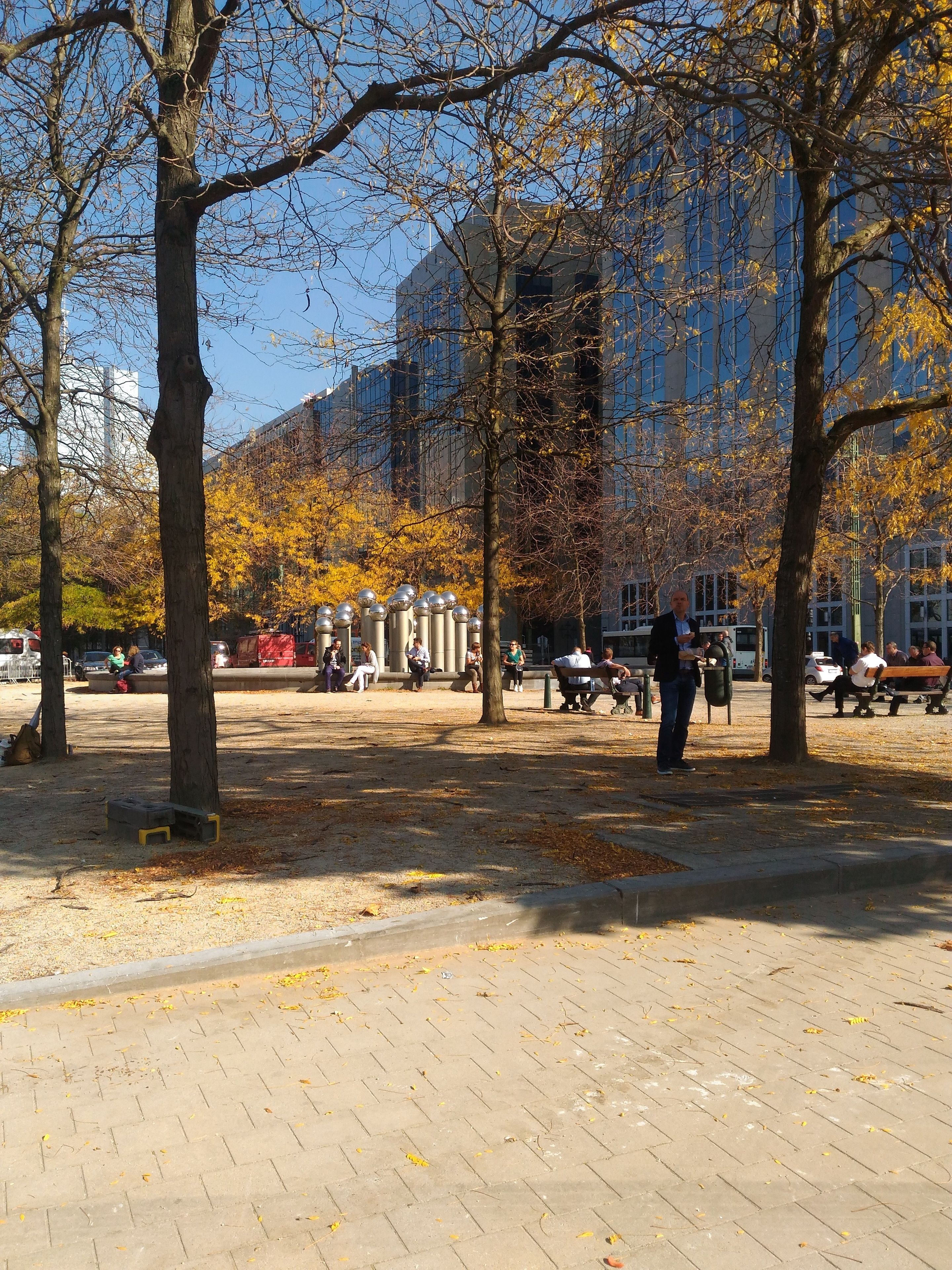 A park with trees, benches, and people.