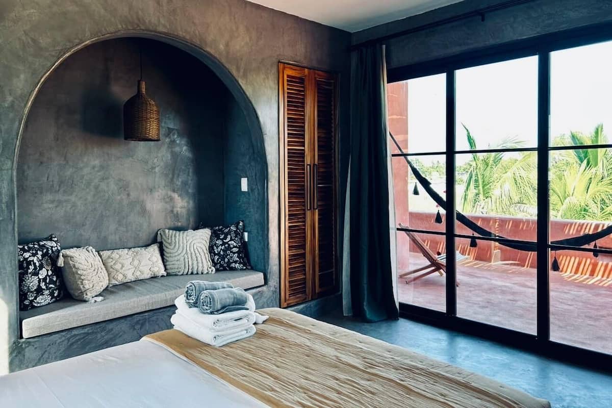 A modern room with a built-in bench, a large window, and a hammock outside.