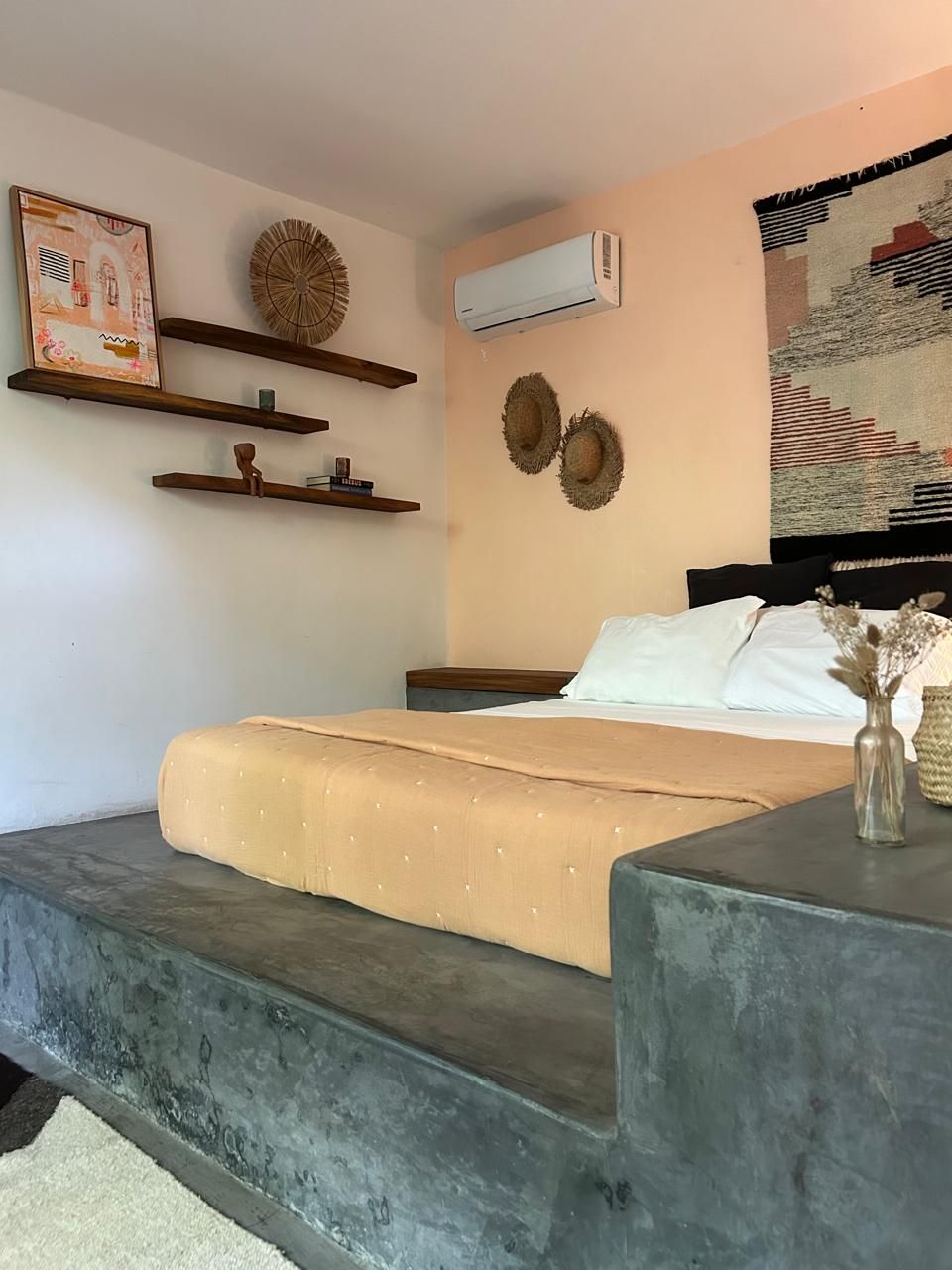 Ein Schlafzimmer mit einem Bett, einer Wand-Klimaanlage und dekorativen Wandbildern.
