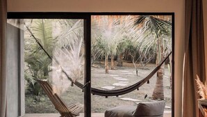 Una sala de estar moderna con un amplio ventanal corredera que da a un jardín tropical.